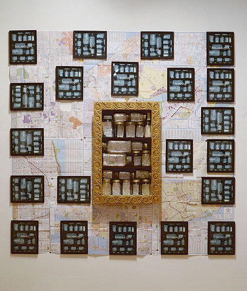 Contained Geographies = Urban Blight, 1994, installation view, C-Prints, maps, jars, shelf, 72 x 72<br><br>I cut out the impoverished area of 21 US cities from the maps, place in a jar, and set on the shelf.