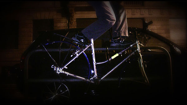 Hitting a Rock in the Road, 2009, video still<br><br>Go to menu, click VIDEOS, to watch excerpts<br><br>Noticing the skeleton of a bicycle locked to a rail on the side of a road in Frankfurt, Germany that I walked past for several days, resonated with me and seemed full of potential.