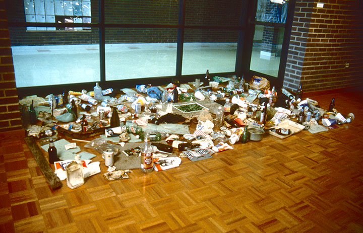 Your Litter Invades Your Space, 1998, installation view, C-Print, 14 x 11, granite, 33 x 22, collected trash, 144 x 84<br><br>Viewers collect trash outside the gallery and place around a photograph of verdant grass on granite.